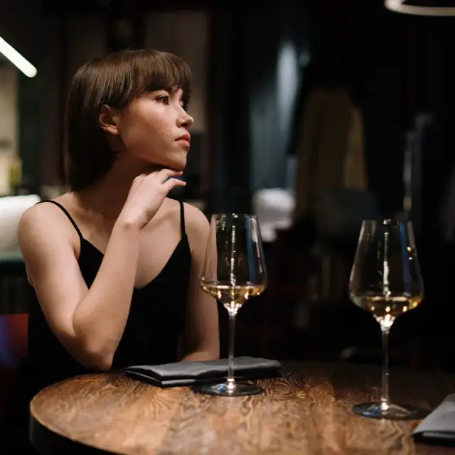 Velada con dos copas de vino blanco en una mesa de madera oscura de MERO 18