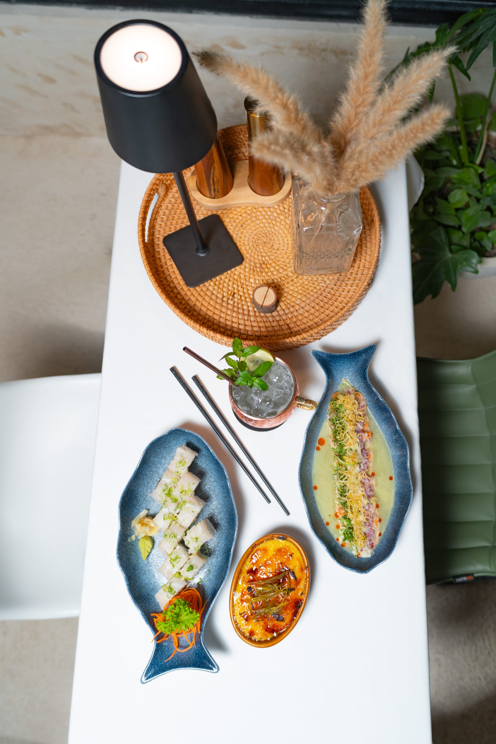 Mesa de MERO 18 vista desde arriba con rollo de sushi, ceviche, crème brûlée y mula de moscú en taza de cobre