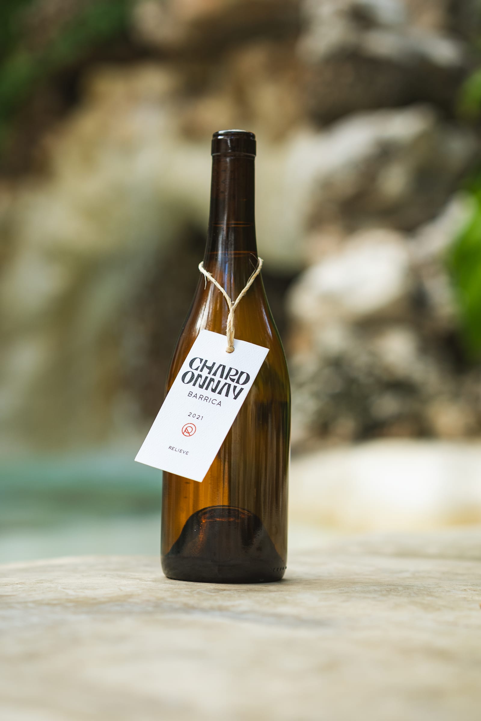 Botella de vino blanco mexicano del Valle de Guadalupe junto a la cascada del jardín de MERO 18 en Cancún, lista para maridar con mariscos