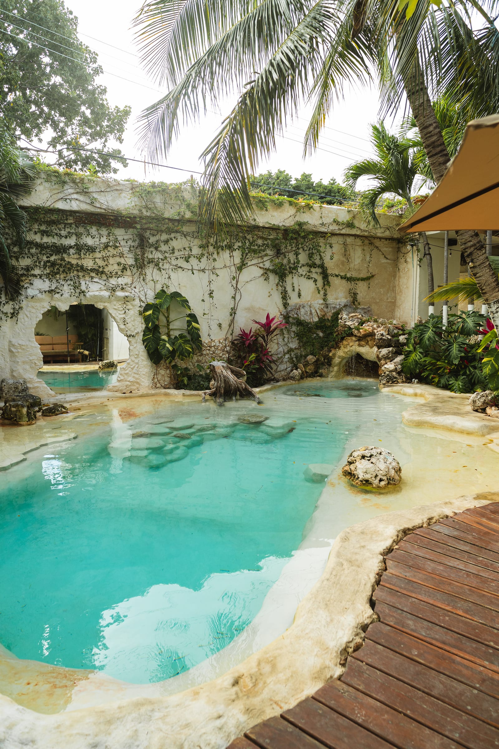 Alberca estilo cenote con cascada de roca y vegetación tropical en un hotel con alberca y spa del Centro de Cancún