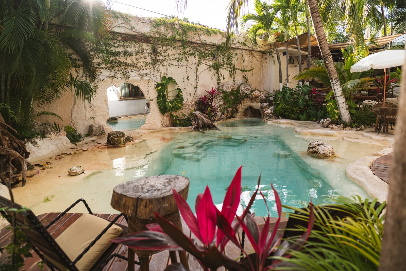 Patio con alberca tipo laguna, agua turquesa, cascada y palmeras en MERO 18, Centro de Cancún