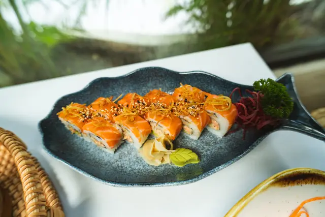 Rollo Salmón con poro frito y ajonjolí en plato con forma de pez
