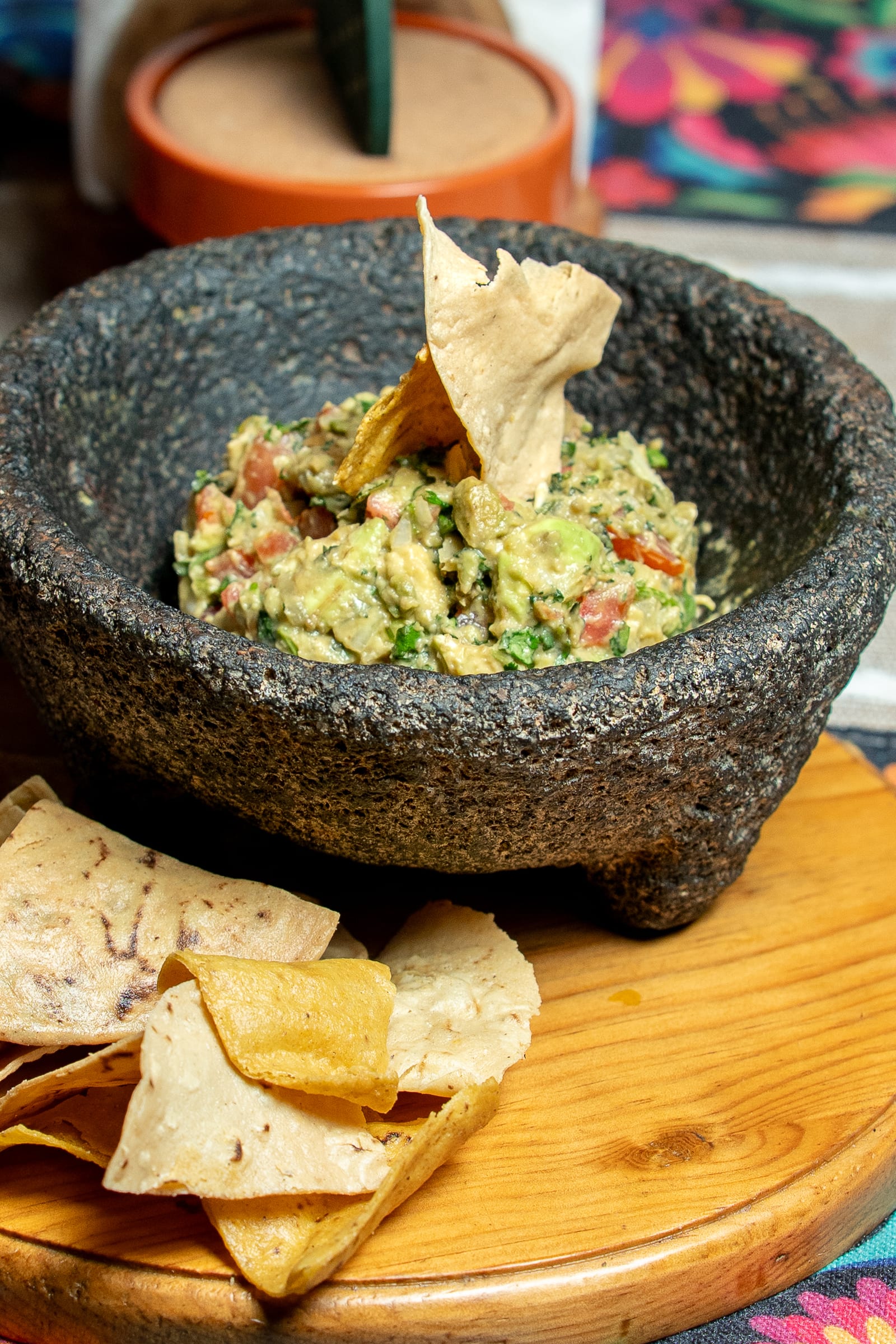 Guacamole con pico de gallo servido en molcajete de piedra volcánica con totopos