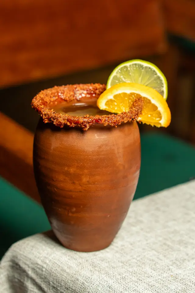 Cóctel de mezcal en jarrito de barro con borde de tajín