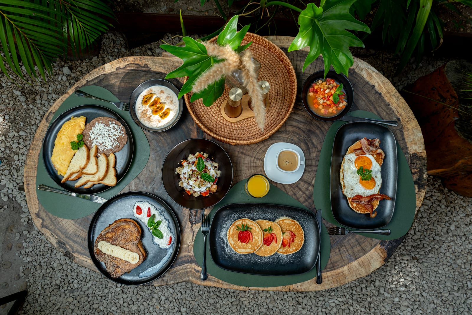 Mesa de desayunos de MERO 18 vista desde arriba: hotcakes con fresas, pan francés con plátano, omelette y jugos frescos